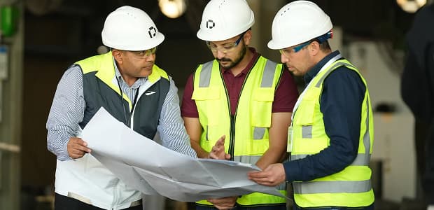 PESCO engineers in hard hats reviewing drawings together